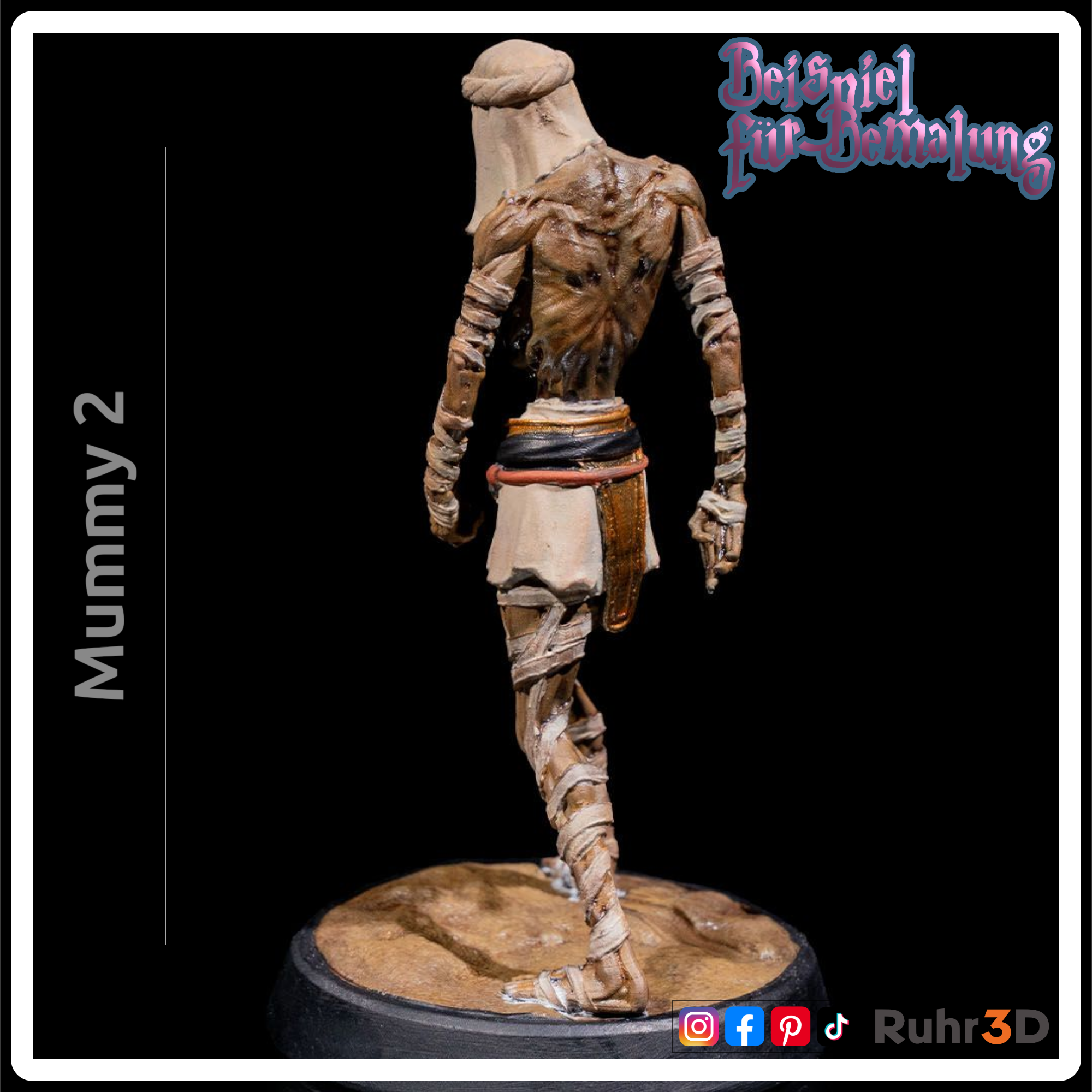 Detaillierte Mumienfigur mit skelettartigem Gesicht und Bandagen. Die Figur hat goldene Akzente an Kragen und Handgelenk sowie einen roten Edelstein am Gürtel. Die Basis ist sandfarben, und die Figur ist mit "Mummy 2" beschriftet.