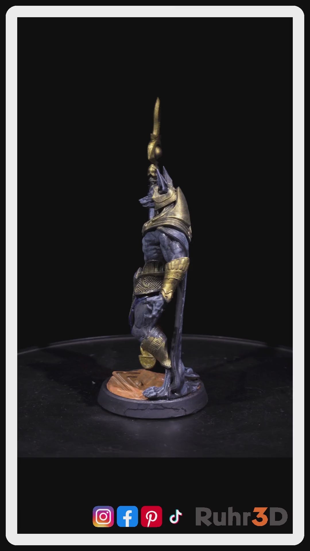 Video der sich drehenden detaillierte Figur des ägyptischen Gottes Anubis, dargestellt als Schakal mit menschlichem Körper. Die Figur hält einen Stab, ist hauptsächlich grau mit goldenen sowie blauen Akzenten und  trägt einem dunkelblauen Umhang. Der Text "Jackal General" befindet sich auf der linken Seite. Das Bild stellt ein Beispiel für die Bemalung der Figur dar.